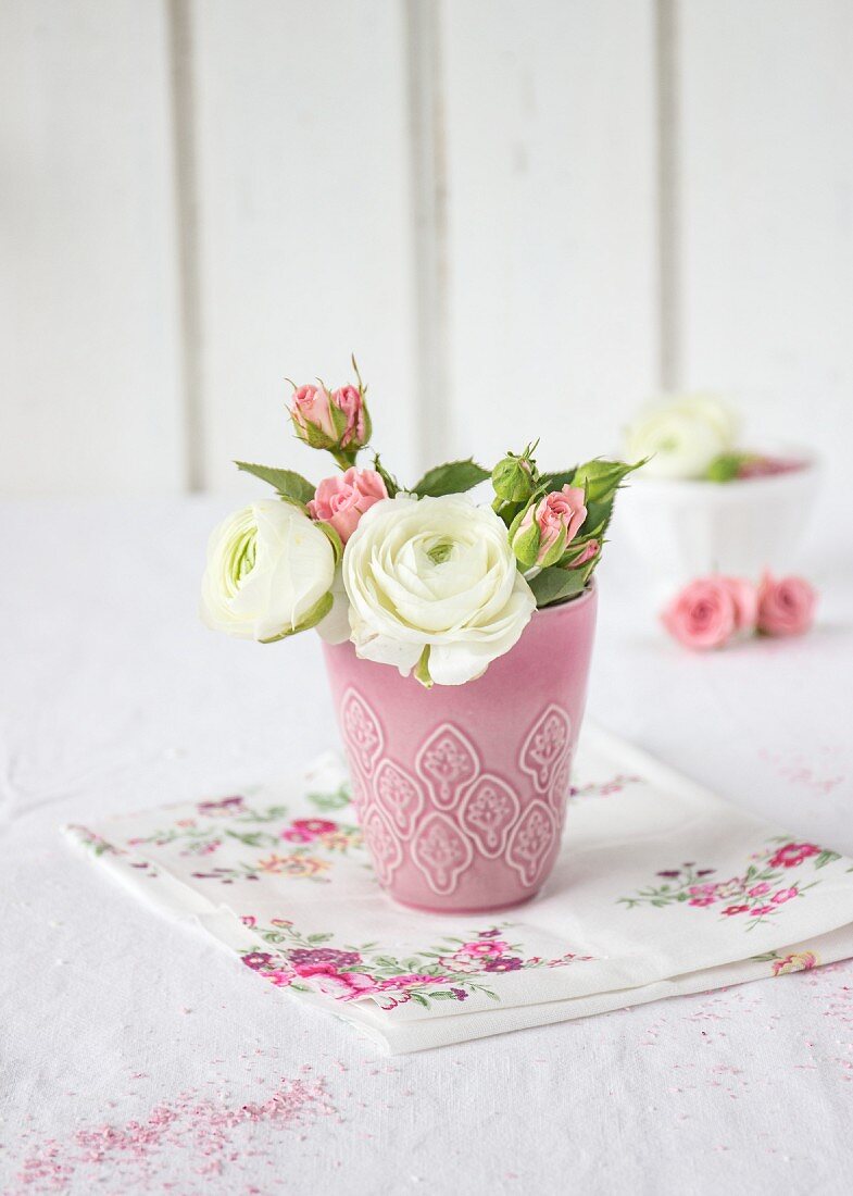 Ranunculus and roses in pink vase