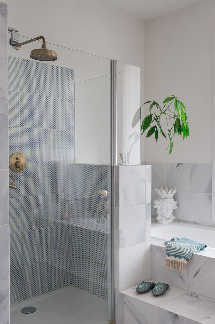Glastür zur Dusche neben eingebauter Wanne mit Marmorfliesen