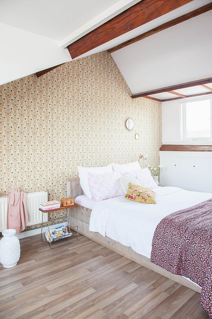 Double bed in attic bedroom with retro wallpaper