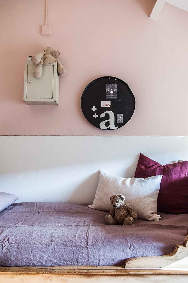 Kinderbett mit Kissen und Teddybär im Mädchenzimmer mit rosa Wand