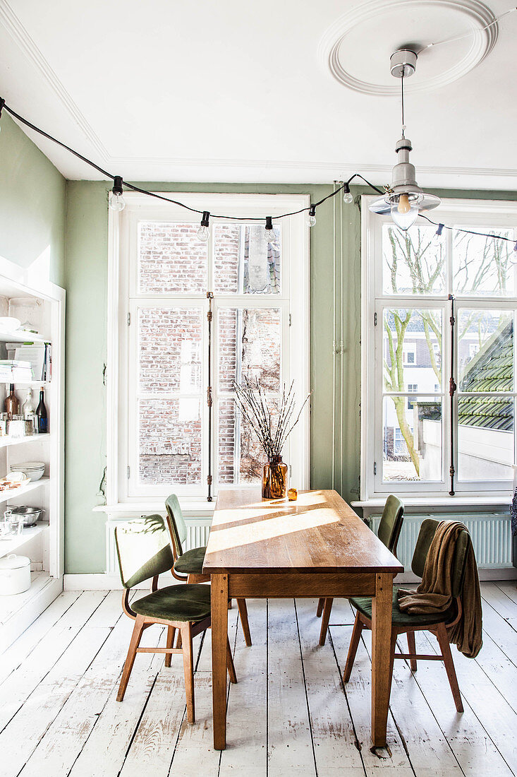 Essbereich mit grüner Wand und weißem Dielenboden, Tisch mit Stühlen vor dem Fenster