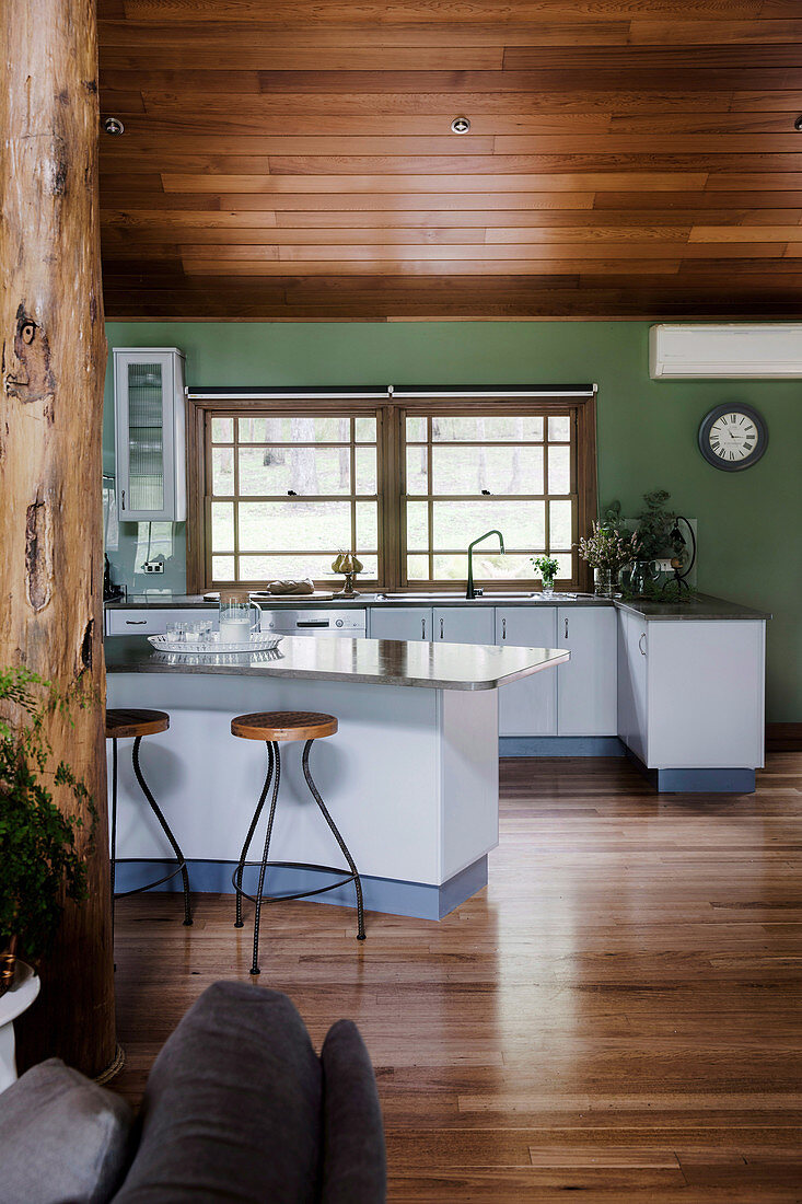 Offene Küche mit geschwungenem Frühstückstresen und grüner Wand