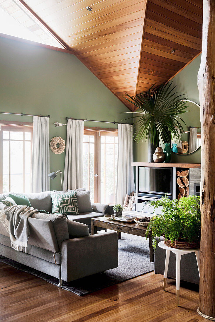 Living room in natural tones with high ceilings and green walls