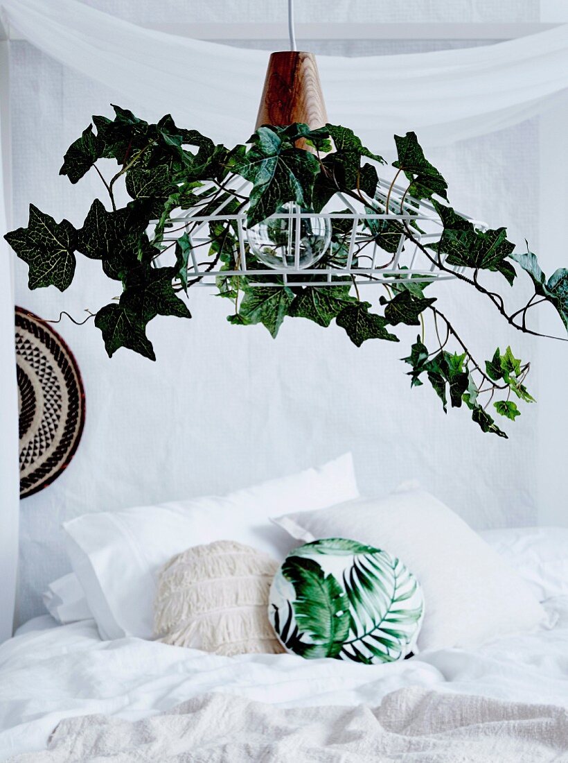 Lampshade decorated with artificial ivy over the bed