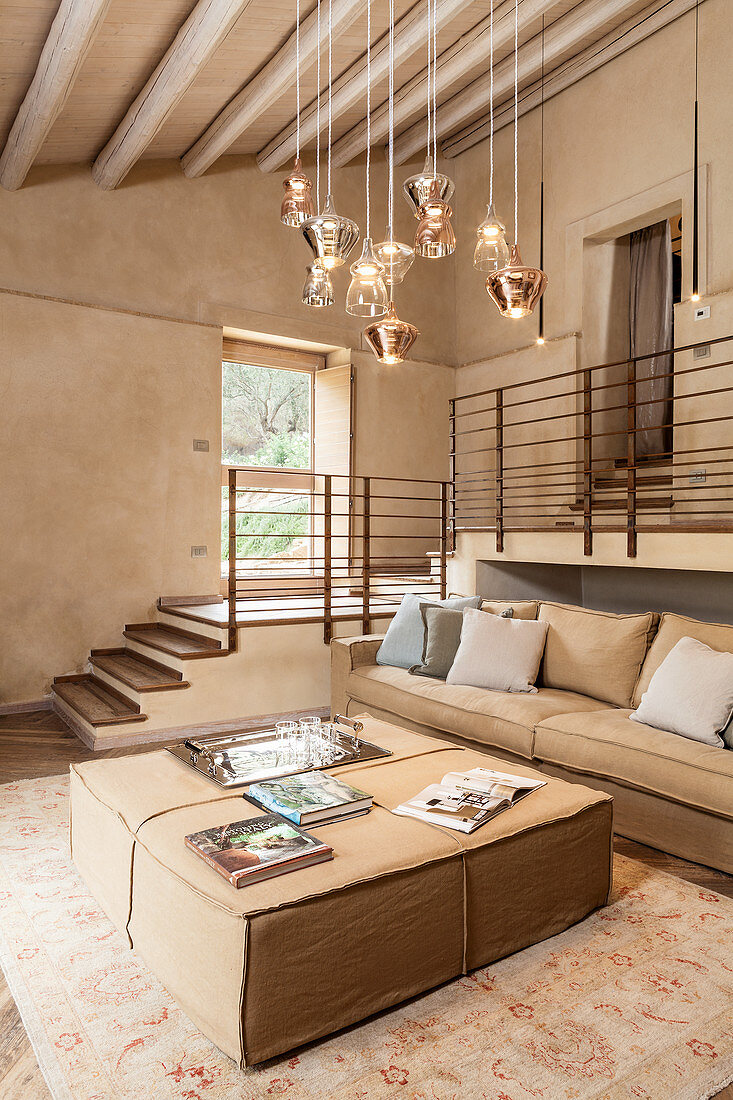 Stillvolles Wohnzimmer mit hellen Polstermöbeln und Designerleuchte, seitlich Zwischengeschoss