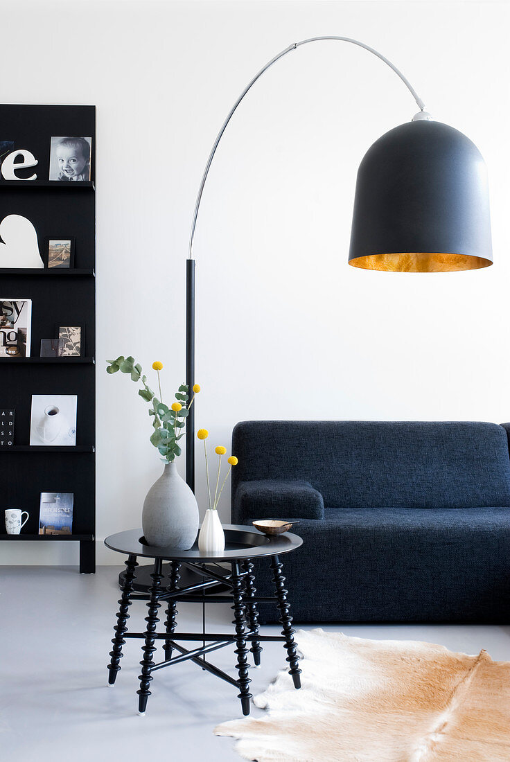 Black arc lamp above sofa and coffee table in living room