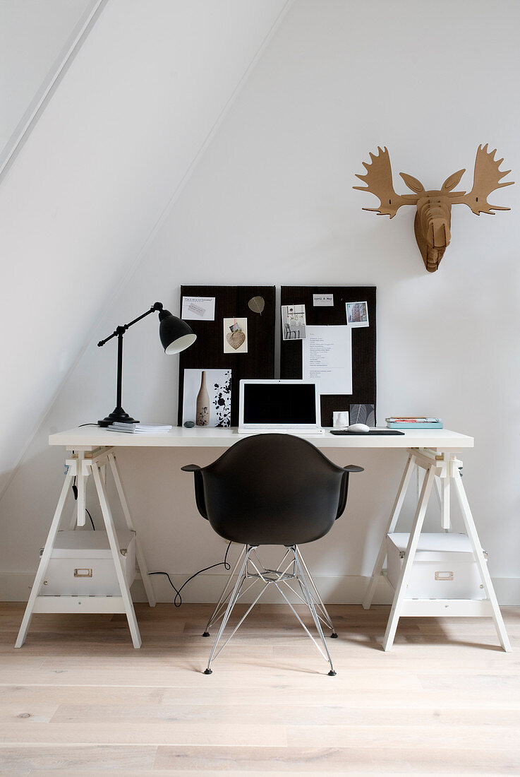 Black shell chair at desk on trestles below sloping ceiling