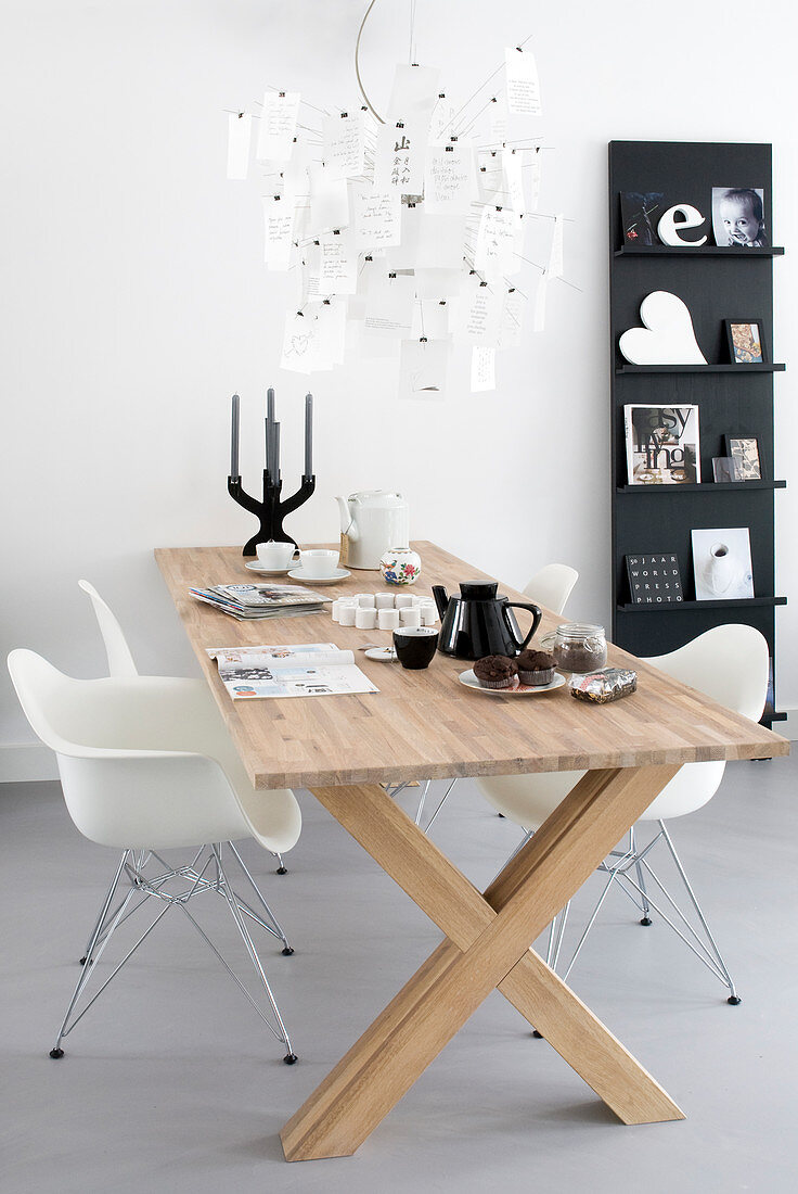 Shell chairs at modern wooden table next to ledge-style bookshelves