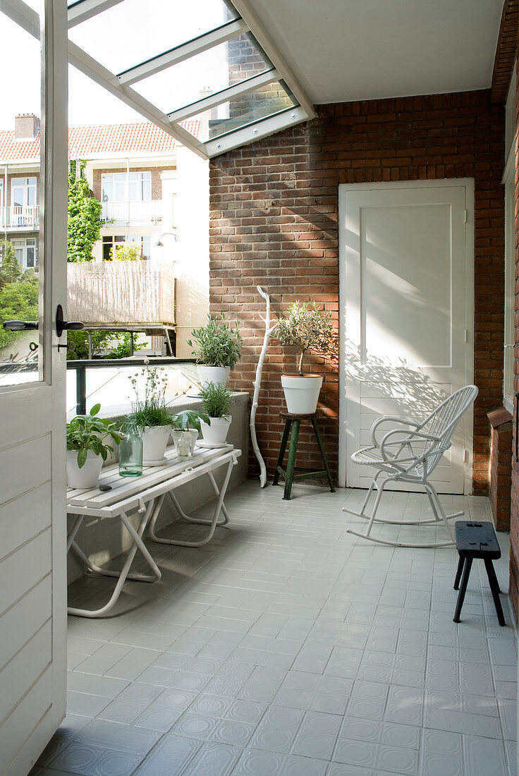 Summery loggia with glass roof, brick wall and white floor