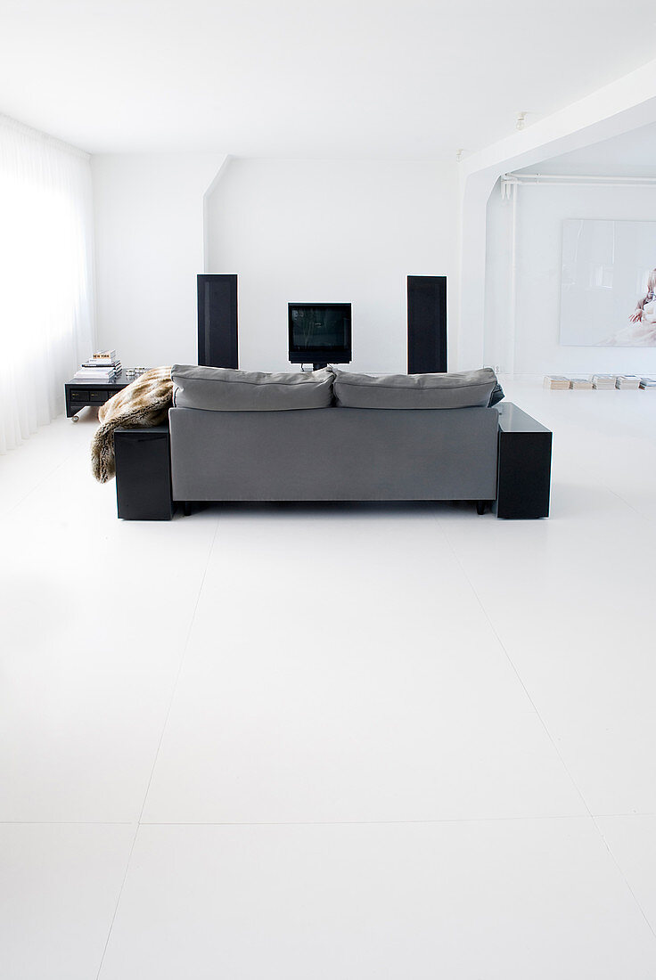 Graues Sofa im minimalistischen Wohnzimmer mit weißem Boden