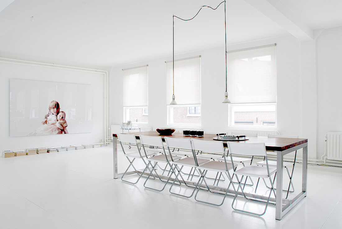 Klappstühle am langen Tisch im minimalistischen Esszimmer mit weißem Boden
