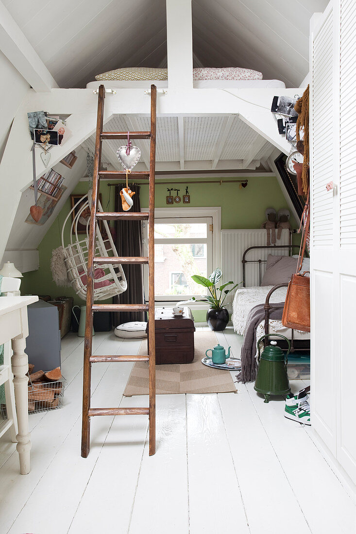 Ladder leading to bed below ceiling in small room decorated in vintage style