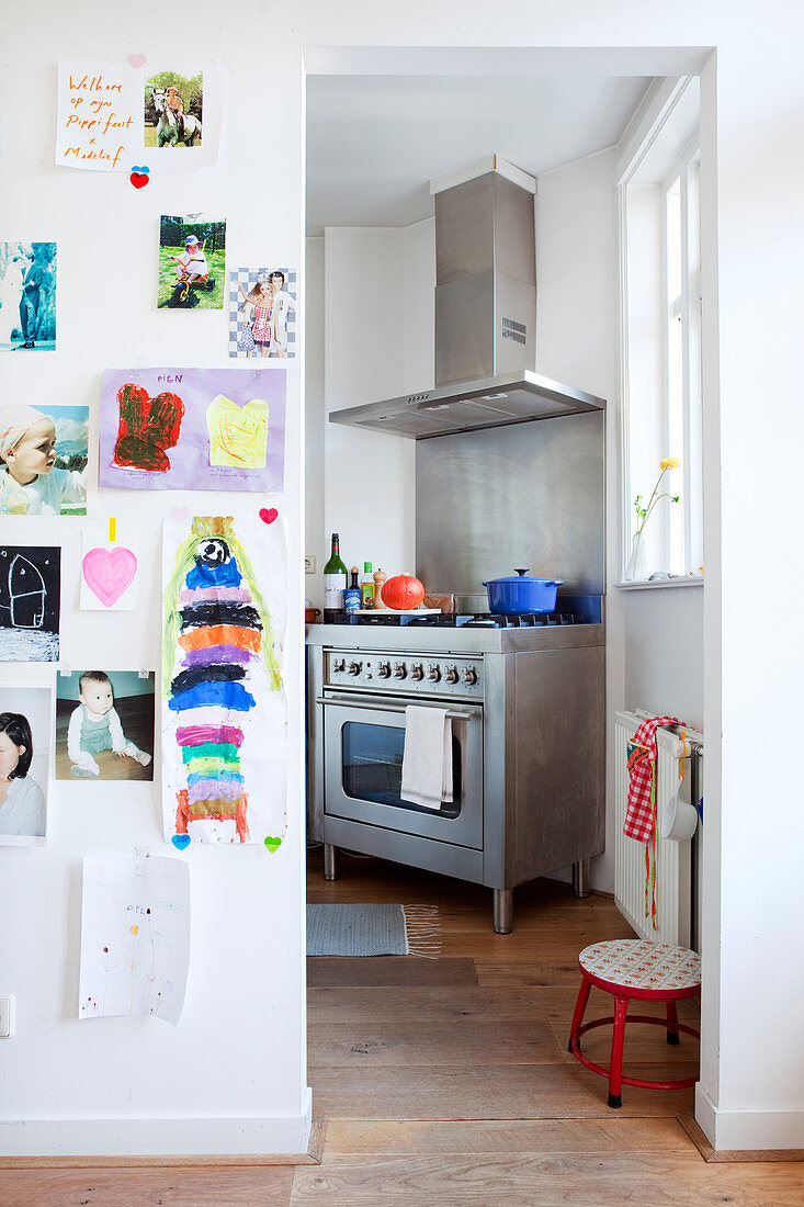 Children's artworks on wall and view of stainless steel cooker in kitchen