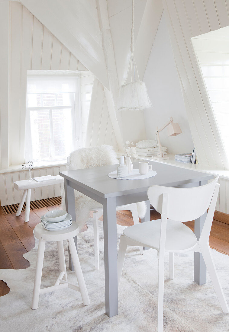 Kleiner Esstisch mit verschiedenen Stühlen in weißer Ambiente