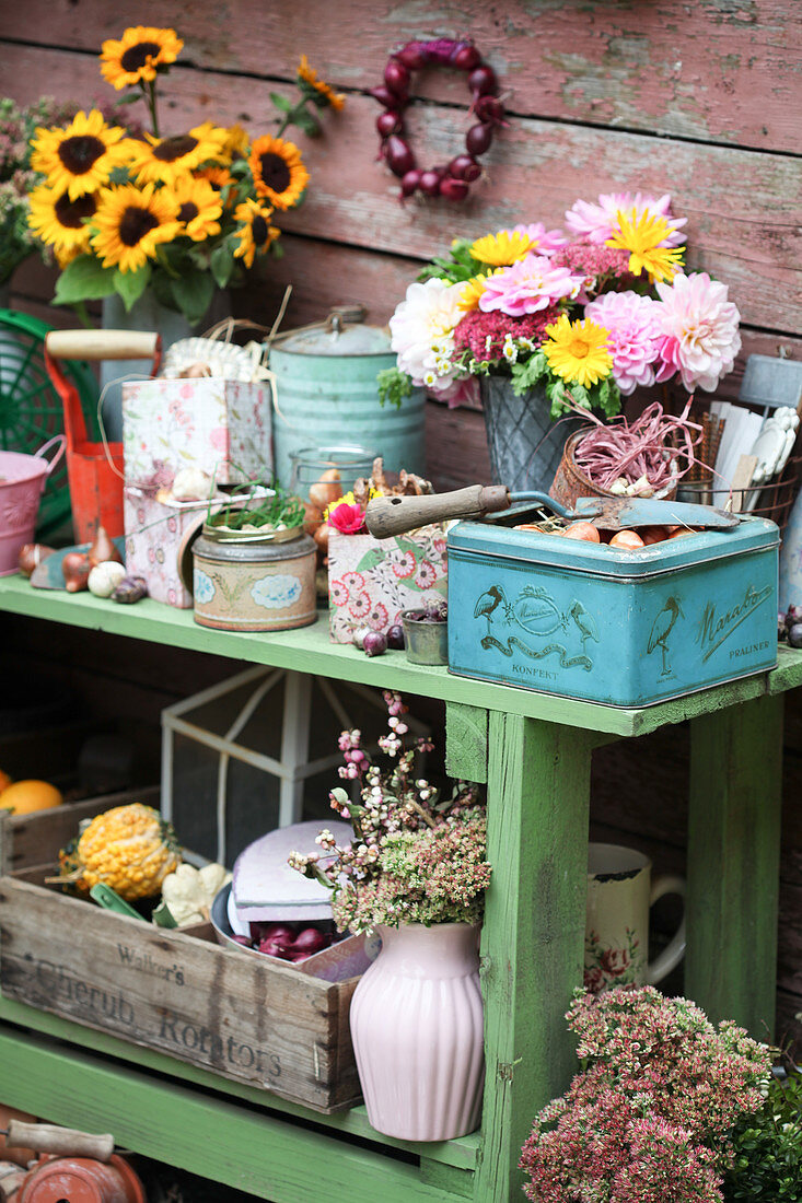 Grüner Pflanztisch mit Vintage-Deko, Herbstblumen und Gartenzubehör