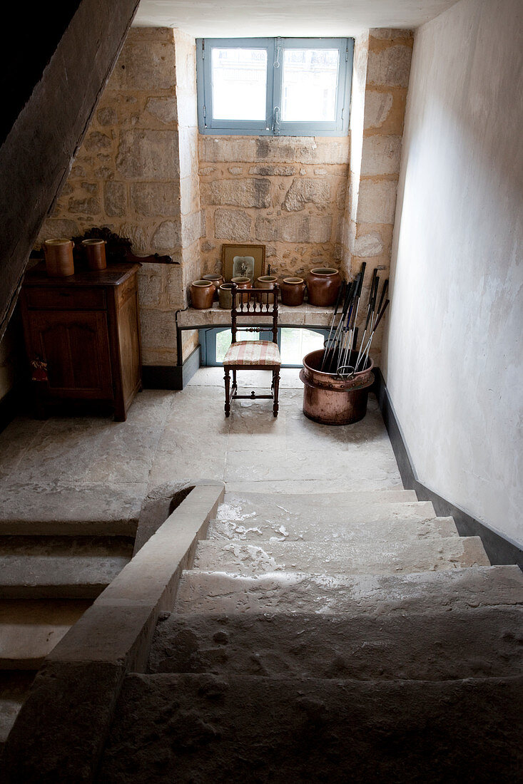 Steinguttöpfe, Stuhl und Schränkchen auf dem Absatz einer alten Steintreppe