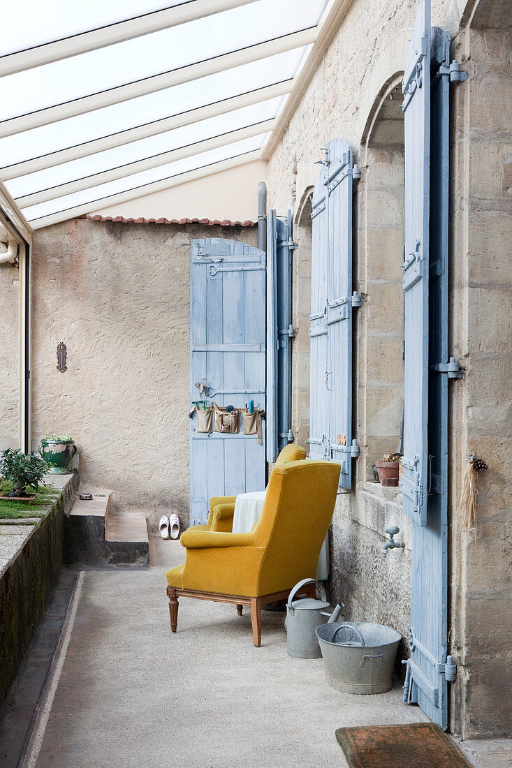 Zwei Ockergelbe Sessel auf überdachter Terrasse eines mediterranen Landhauses