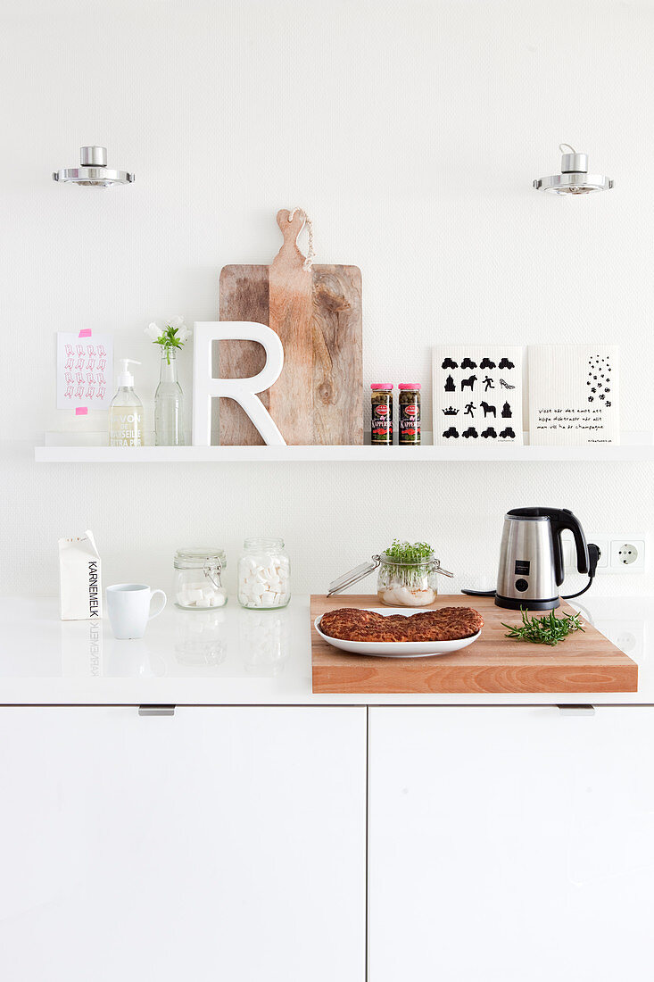 Buchstabe R und Brett auf Bilderleiste in weißer Küche über der Arbeitsplatte