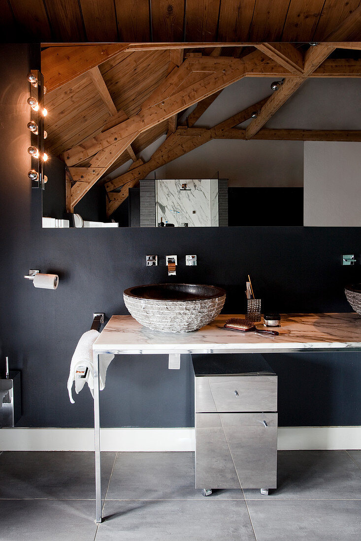 Filigraner Waschtisch und Spiegel an schwarzer Wand mit Holzdecke