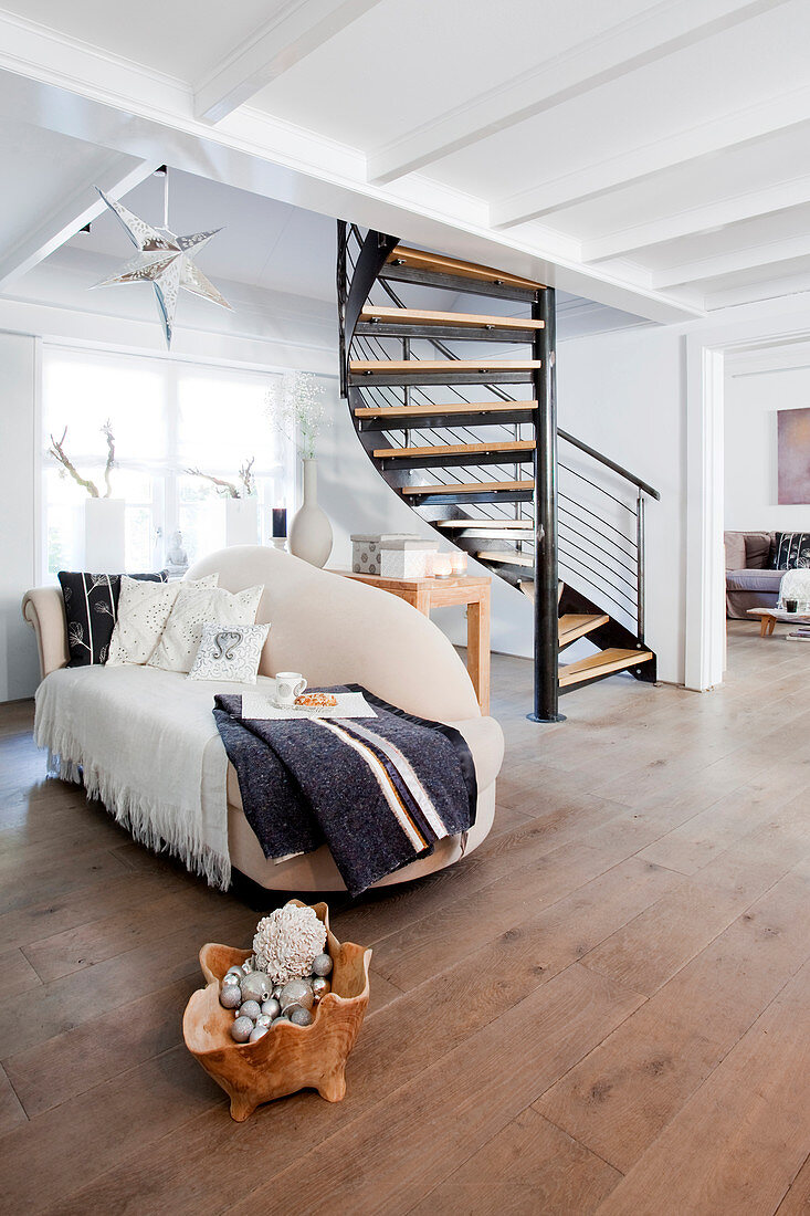 Organisch geformte Couch in hellem, offenem Wohnraum vor Wendeltreppe