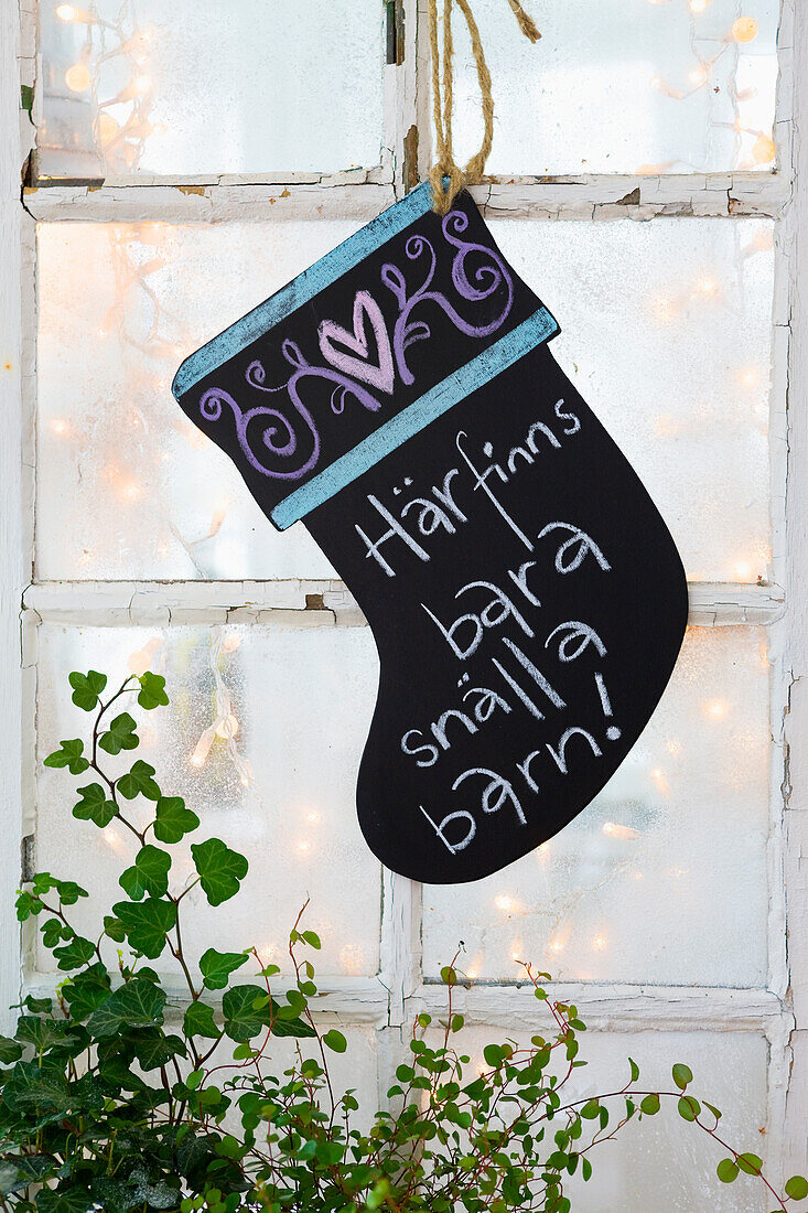 Black chalkboard painted wooden Christmas boot with a message