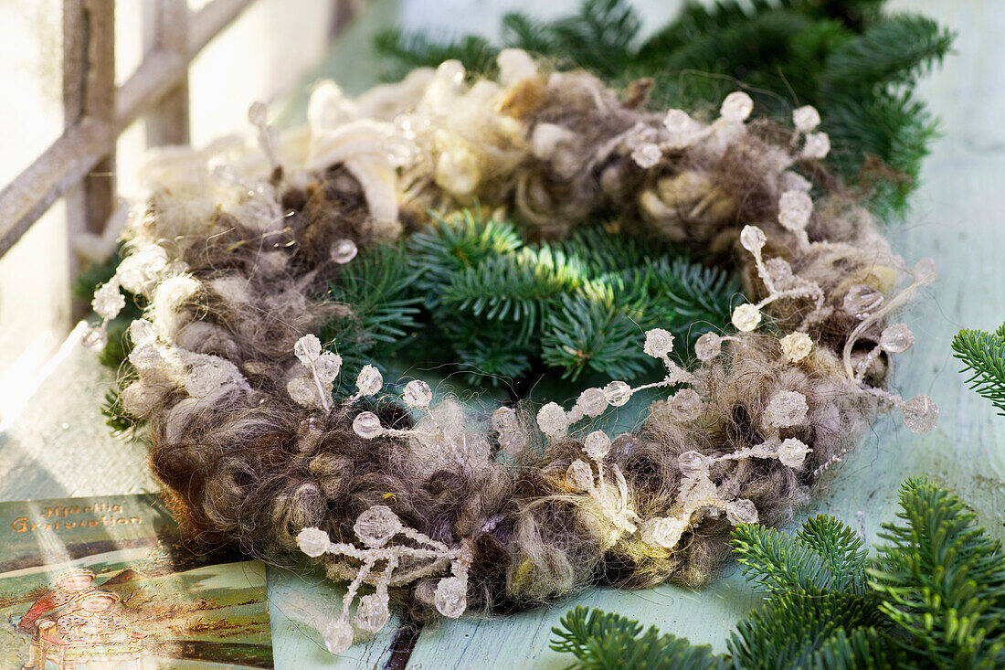 Weihnachtskranz mit Schafwolle und Perlengirlande umwickelt