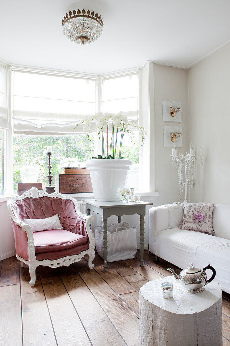 Gemütlicher Sessel, großer Blumentopf mit Orchiedeen auf Holztisch im Erkerbereich