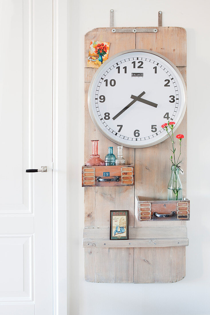Clock and small vases mounted on wooden board on wall