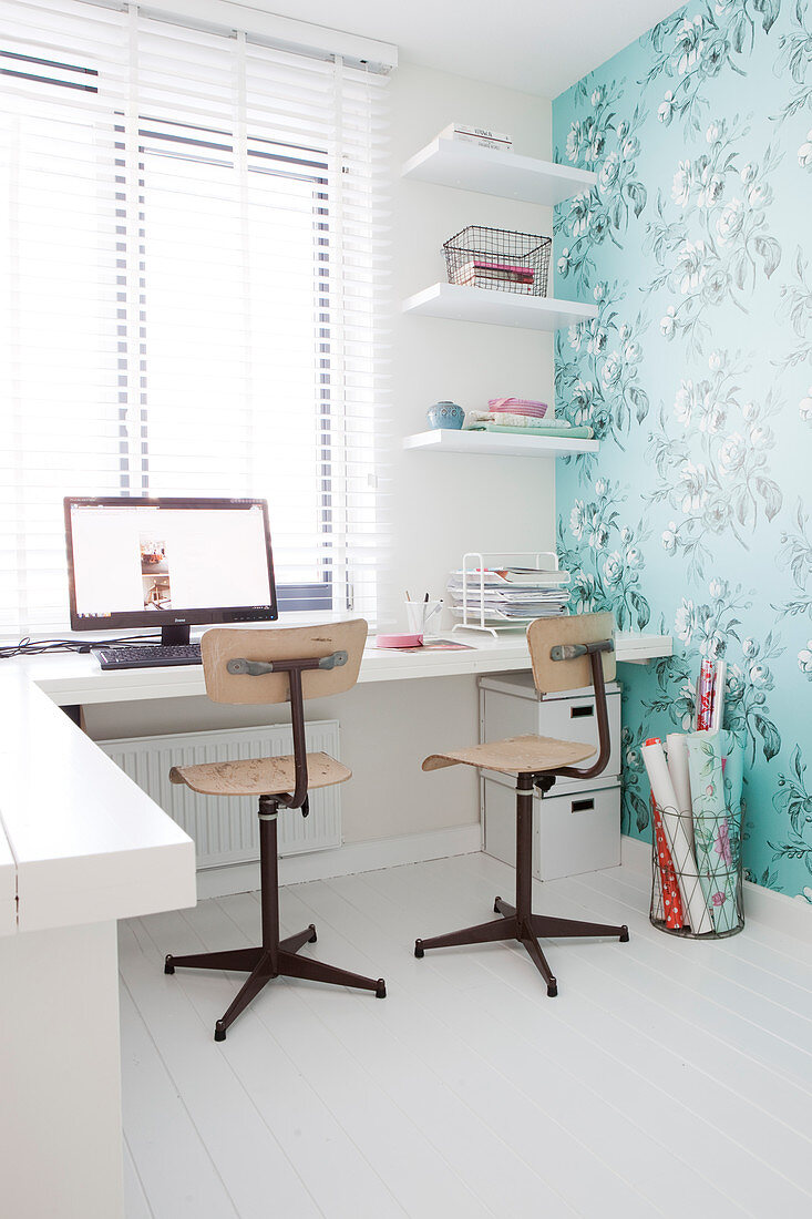 Schreibtisch mit zwei Stühlen im Arbeitszimmer mit türkisfarbener Blumentapete