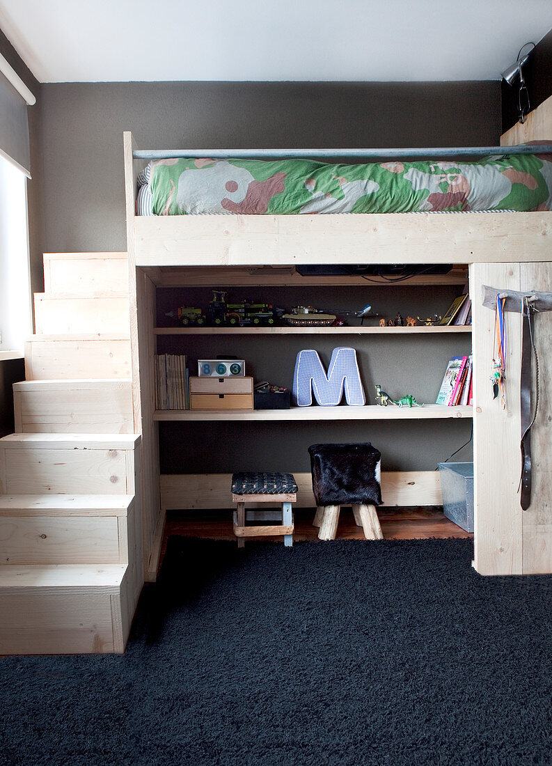 Loft bed with pale wooden steps and shelves below in child's bedroom