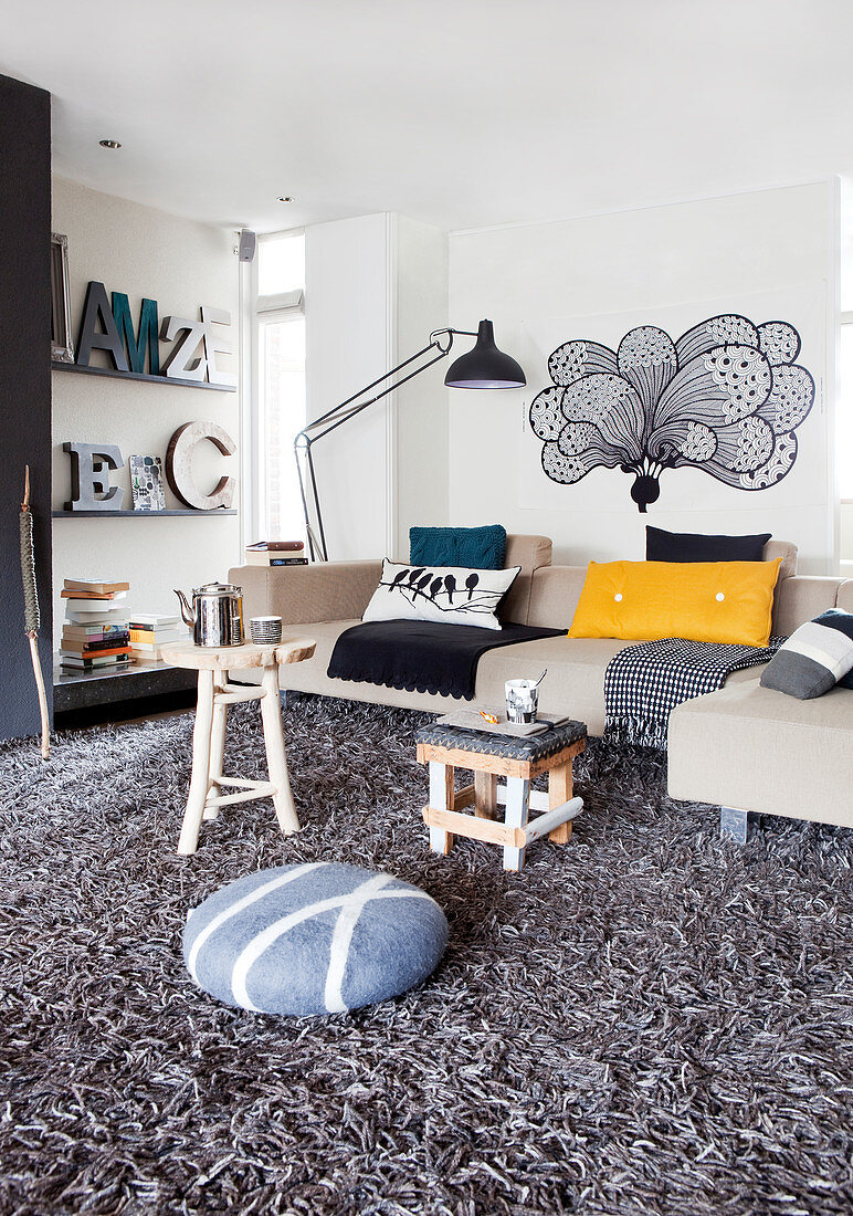 Pale sofa set and decorative letters on shelves in living room with grey long-pile rug