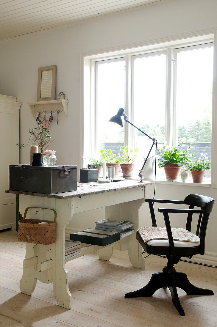 Alter Drehstuhl und Schreibtisch mit Vintage-Deko am Fenster