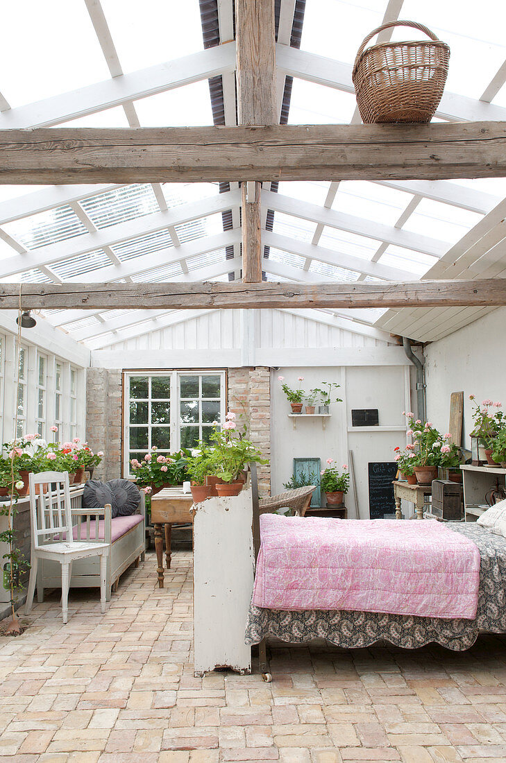 Conservatory with brick floor and glass roof as a guest house with bed