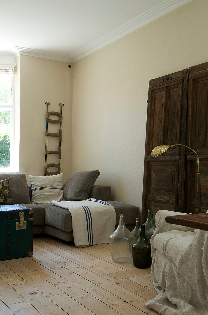 Wohnzimmer in Naturtönen mit altem Türblatt und Weinballons als Deko