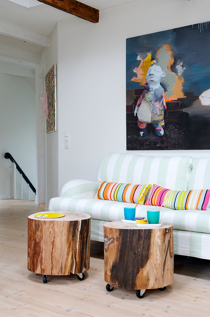 Selbstgemachte Beistelltische aus Baumscheiben auf Möbelrollen vorm Sofa
