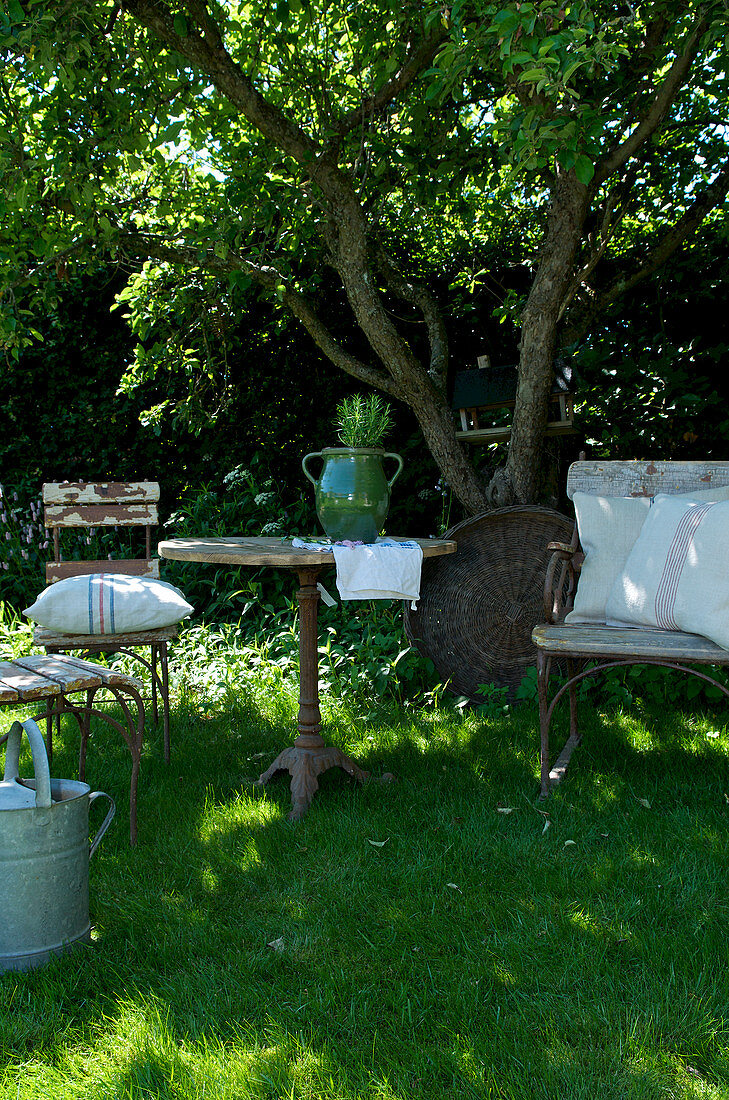 seating area with old garden furniture on the meadow in the summer garden