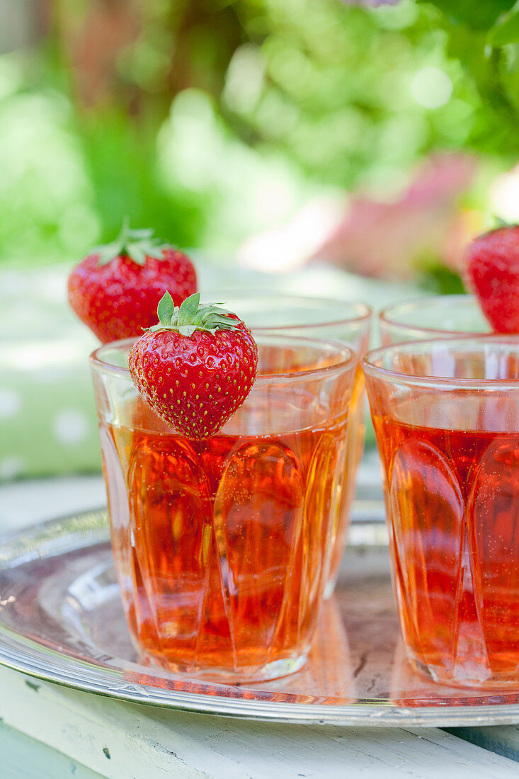 Erdbeeren an Trinkgläsern mit Erdbeersirup-Getränk