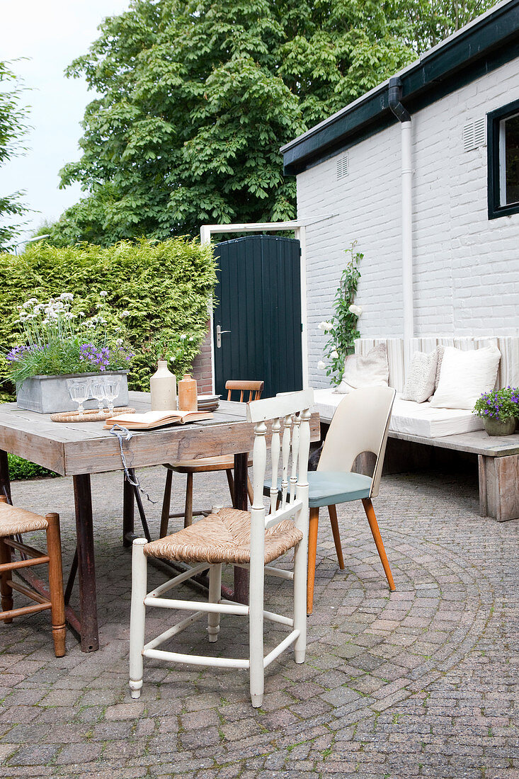 Rustikaler Holztisch mit Stühlen auf gepflastertem Terrassenplatz