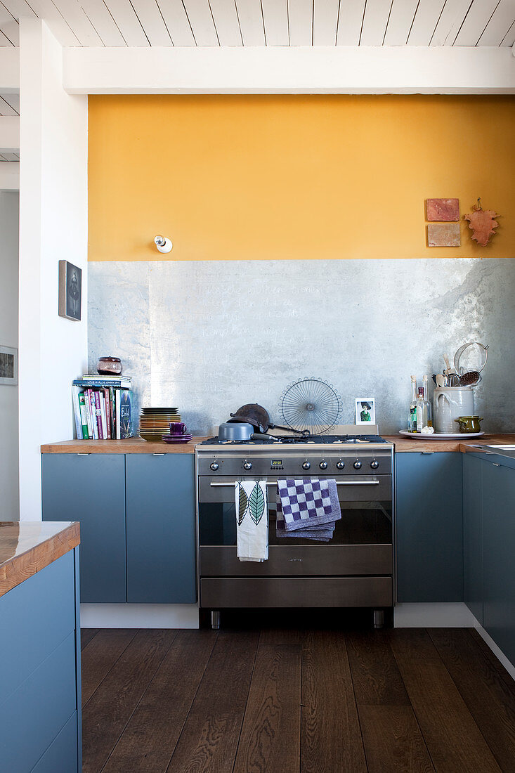 Wohnküche mit blau-grauen Unterschränken und gelber Wand