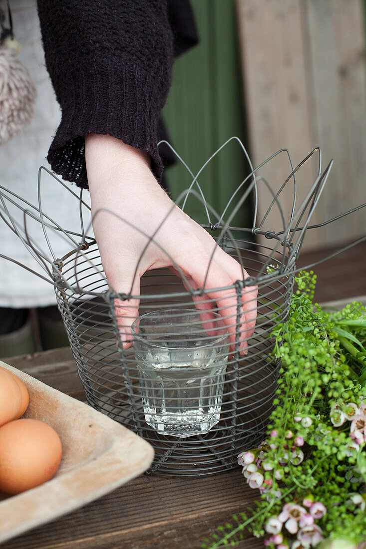 Woman placing glass of water in metal basket