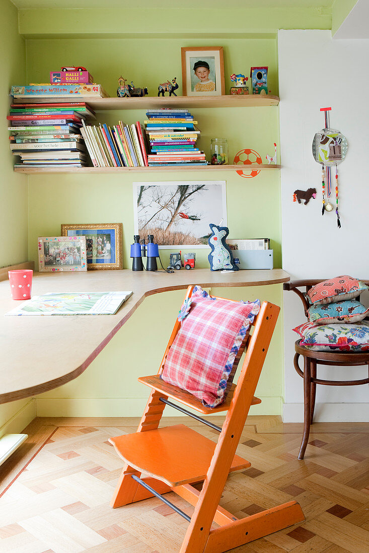 Kinderstuhl am Schreibtisch und Regale an grüner Wand