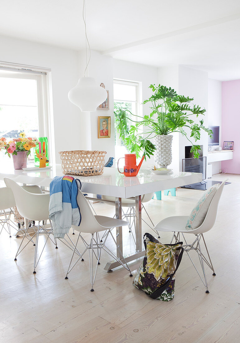 Esstisch mit weißen Klassikerstühlen in offenem Wohnraum