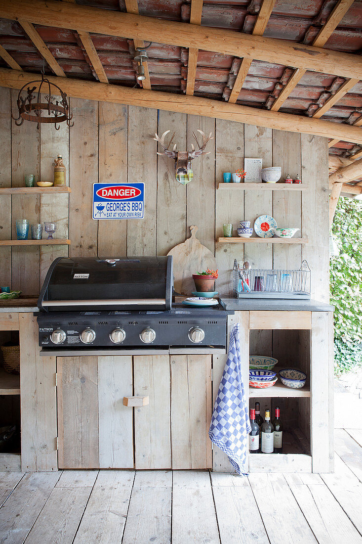 Outdoor-Küche auf überdachter Terrasse mit Bretterwand