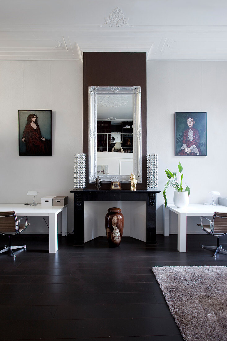 Mirror above the faux fireplace, flanked by white desks and paintings