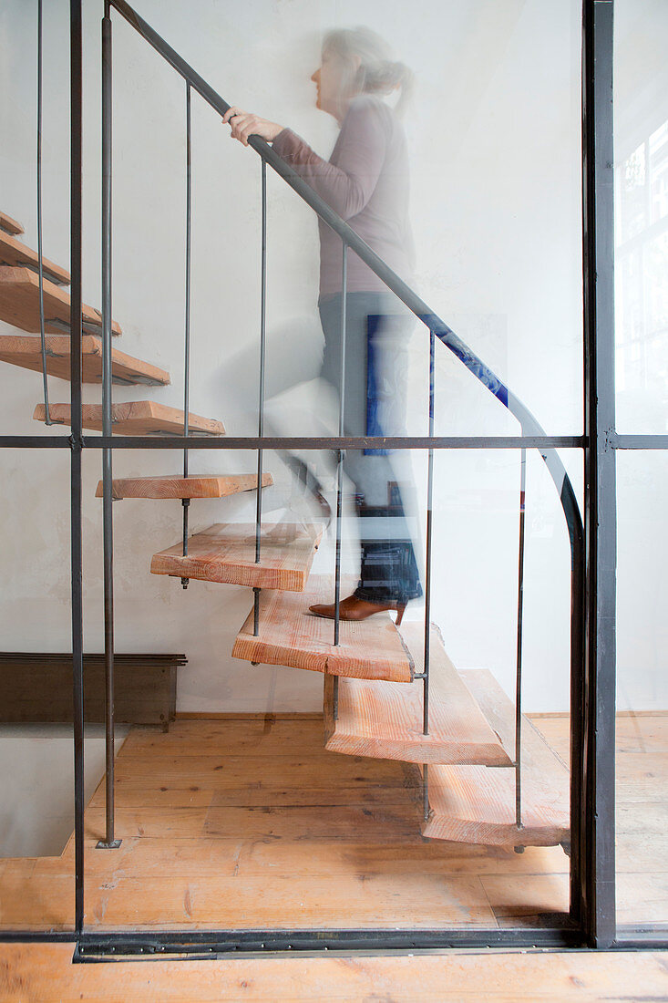 Woman walking up staircase behind glass wall