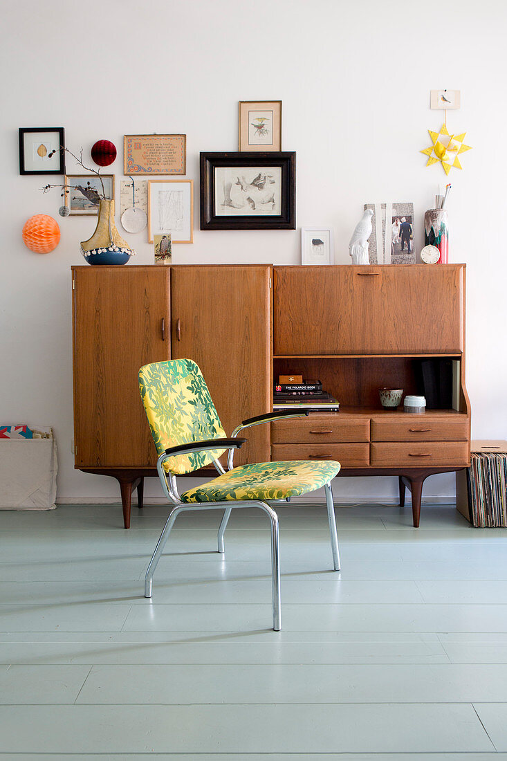 Stuhl vor Retro Sideboard im Wohnzimmer mit Holzdielenboden