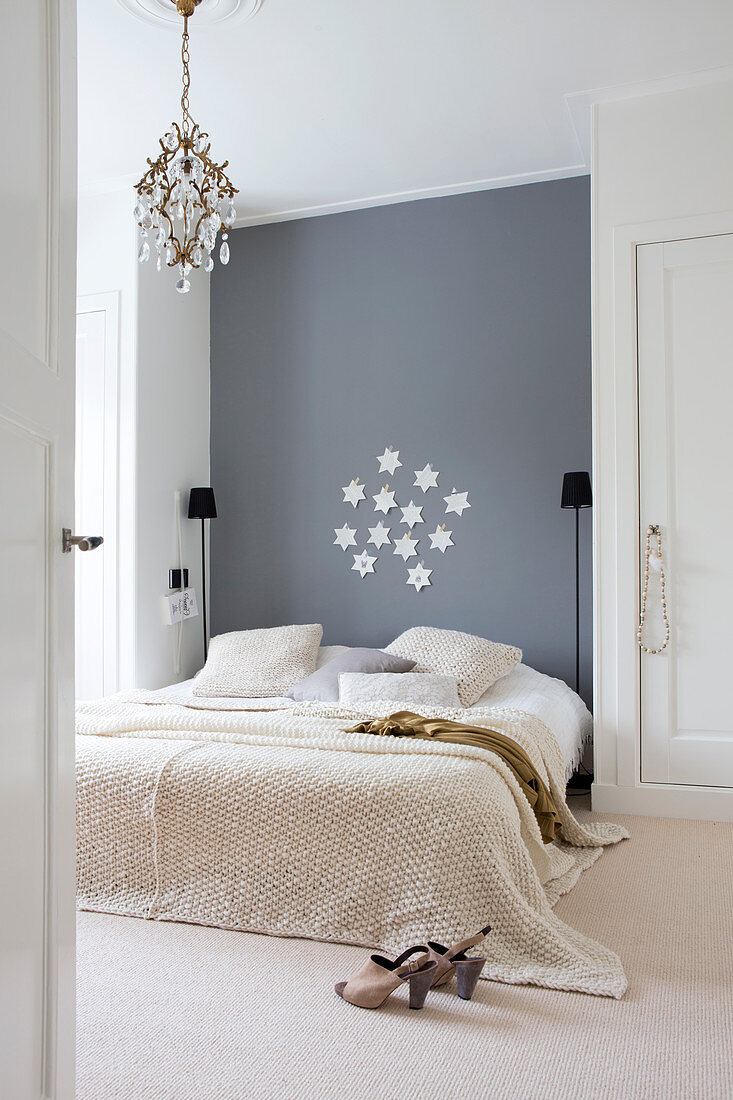 Bett an grauer Wand zwischen zwei Wandschränken im schlichten Schlafzimmer