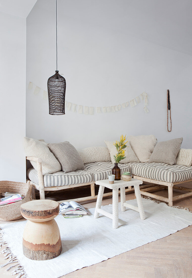 Sitting area with cushions and pillows in natural tones, above a black hanging lamp