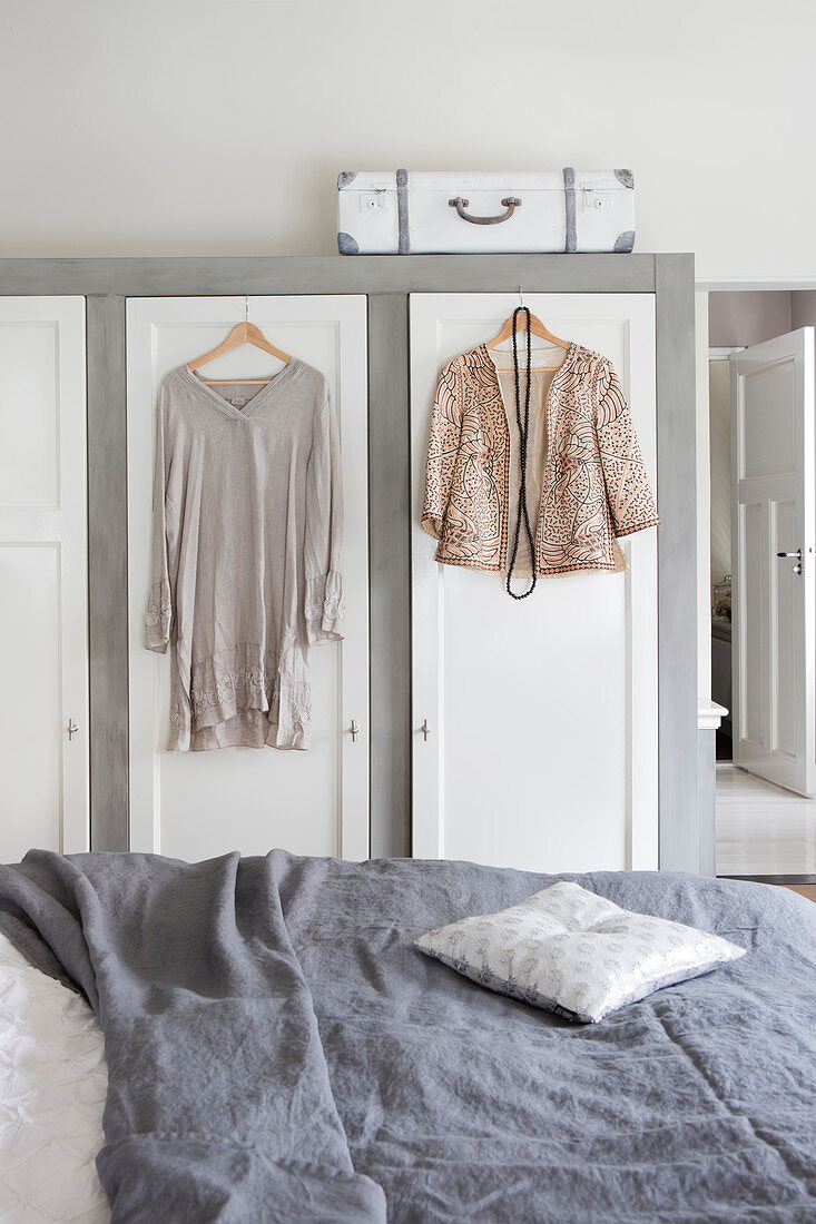 Blazer und Kleid hängen am Kleiderschrank im Schlafzimmer in Grau und Weiß