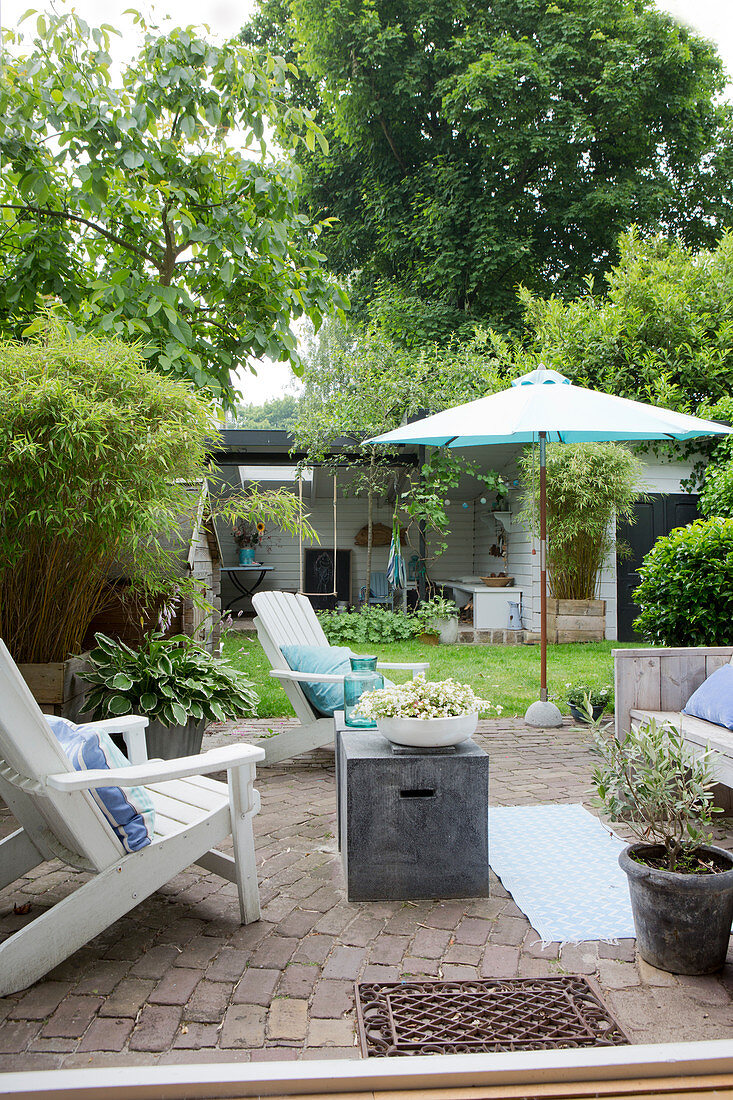 Deckchairs auf gepflasterter Terrasse im sommerlichen Garten